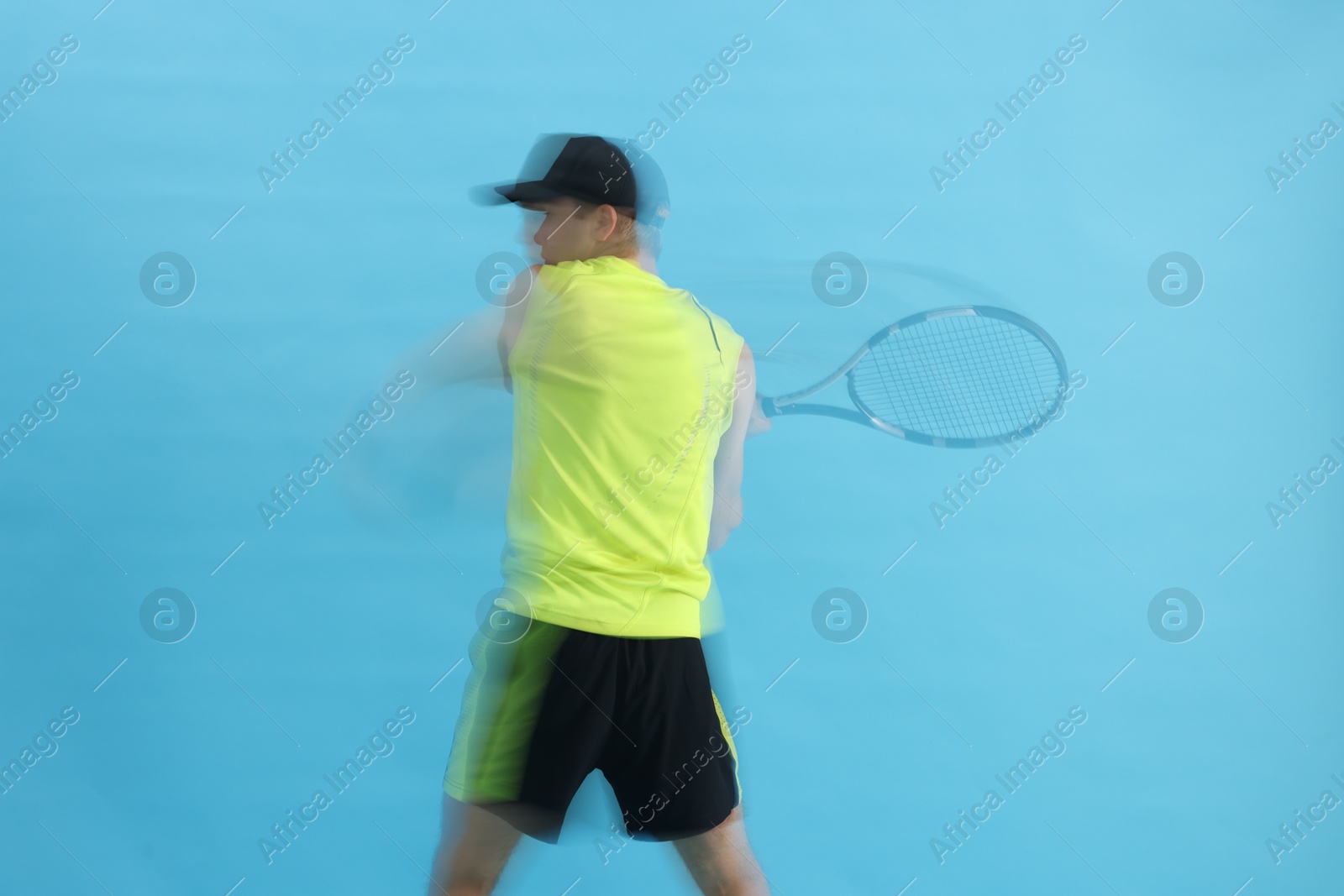 Man with racket playing tennis on light blue background, motion blur effect Photo of Man with racket playing tennis on light blue background, motion blur effect