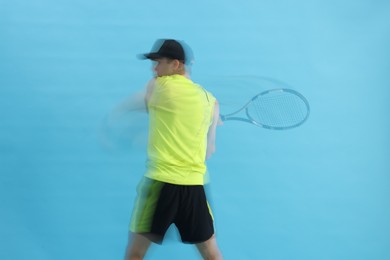 Photo of Man with racket playing tennis on light blue background, motion blur effect