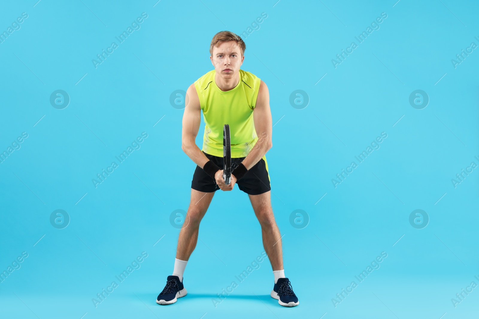Man with tennis racket on light blue background Photo of Man with tennis racket on light blue background