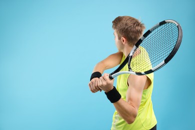 Photo of Man with tennis racket on light blue background, space for text