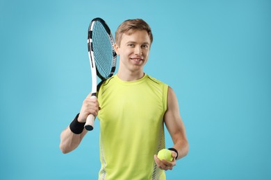 Photo of Man with tennis racket and ball on light blue background