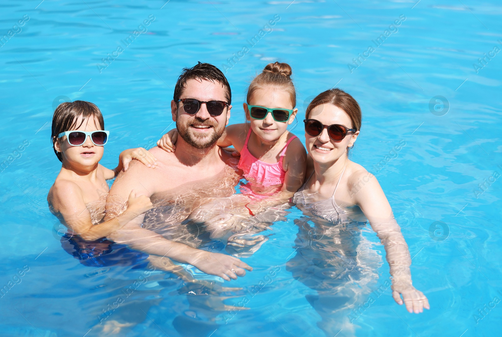 Happy family resting in swimming pool outdoors Photo of Happy family resting in swimming pool outdoors