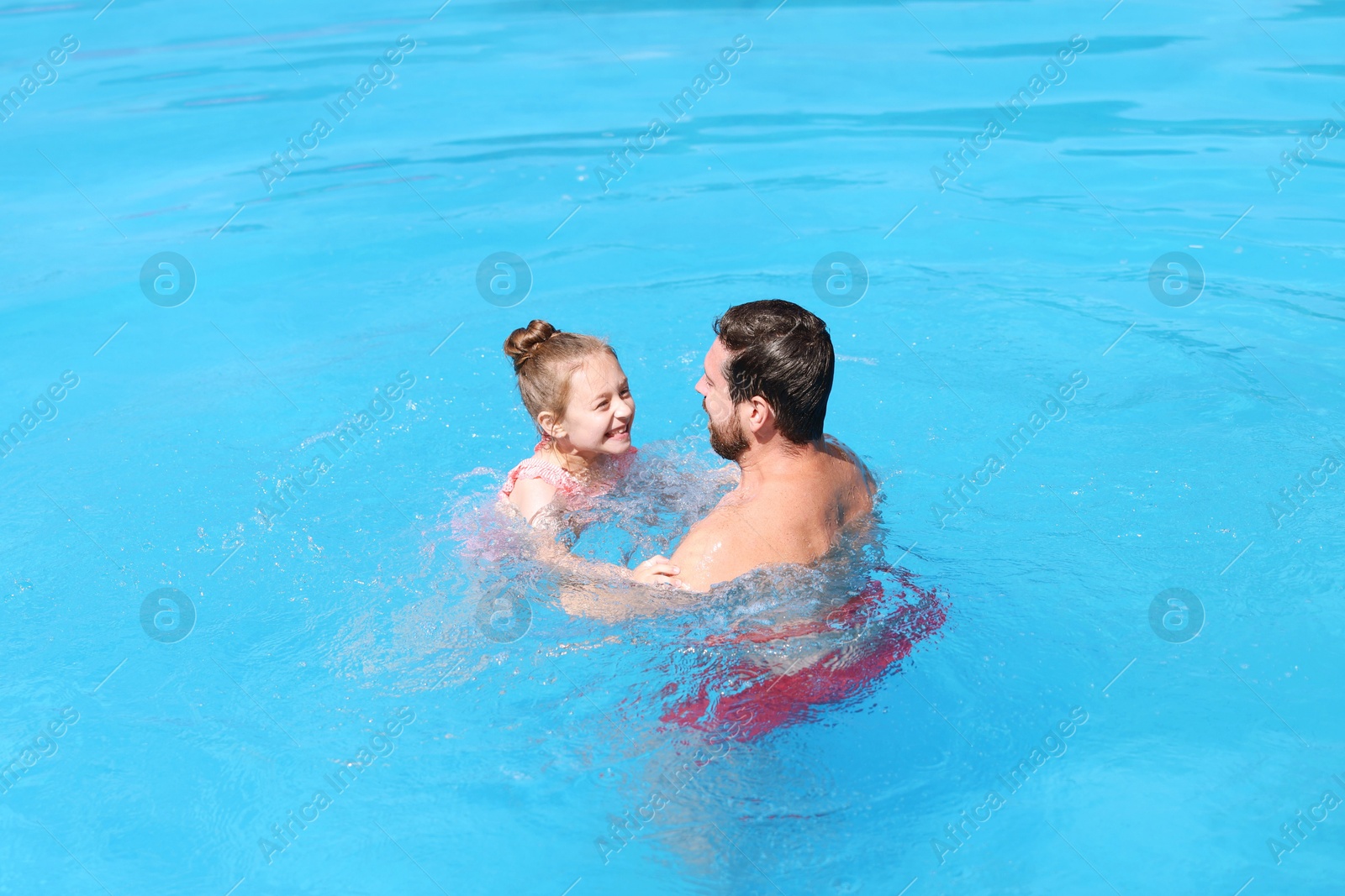 Father and his daughter having fun in swimming pool outdoors. Family vacation Photo of Father and his daughter having fun in swimming pool outdoors. Family vacation