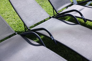 Photo of Sunbeds on green grass outdoors on sunny day, closeup