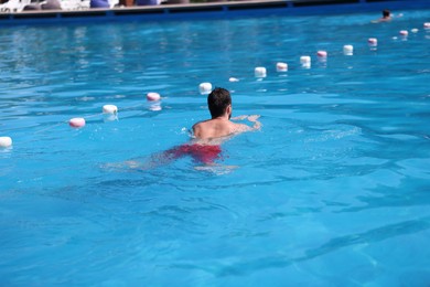 Photo of Man swimming in pool outdoors, back view