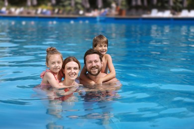 Photo of Happy family resting in swimming pool outdoors, space for text