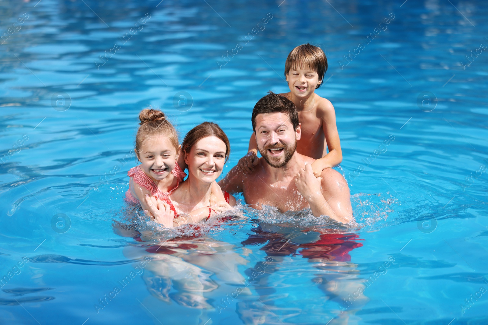 Happy family resting in swimming pool outdoors Photo of Happy family resting in swimming pool outdoors