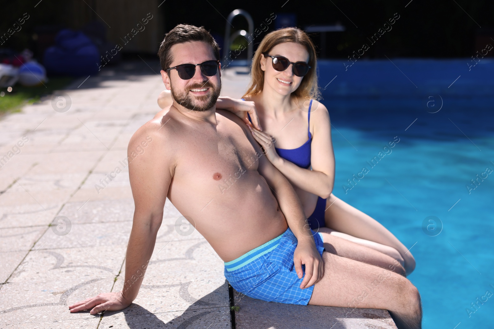 Happy couple at poolside outdoors on sunny day. Family vacation Photo of Happy couple at poolside outdoors on sunny day. Family vacation