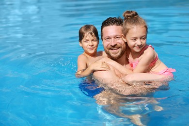 Photo of Happy father and his kids resting in swimming pool outdoors, space for text. Family vacation