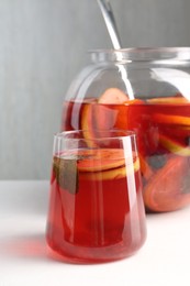 Photo of Tasty fruity punch on white table. Refreshing drink