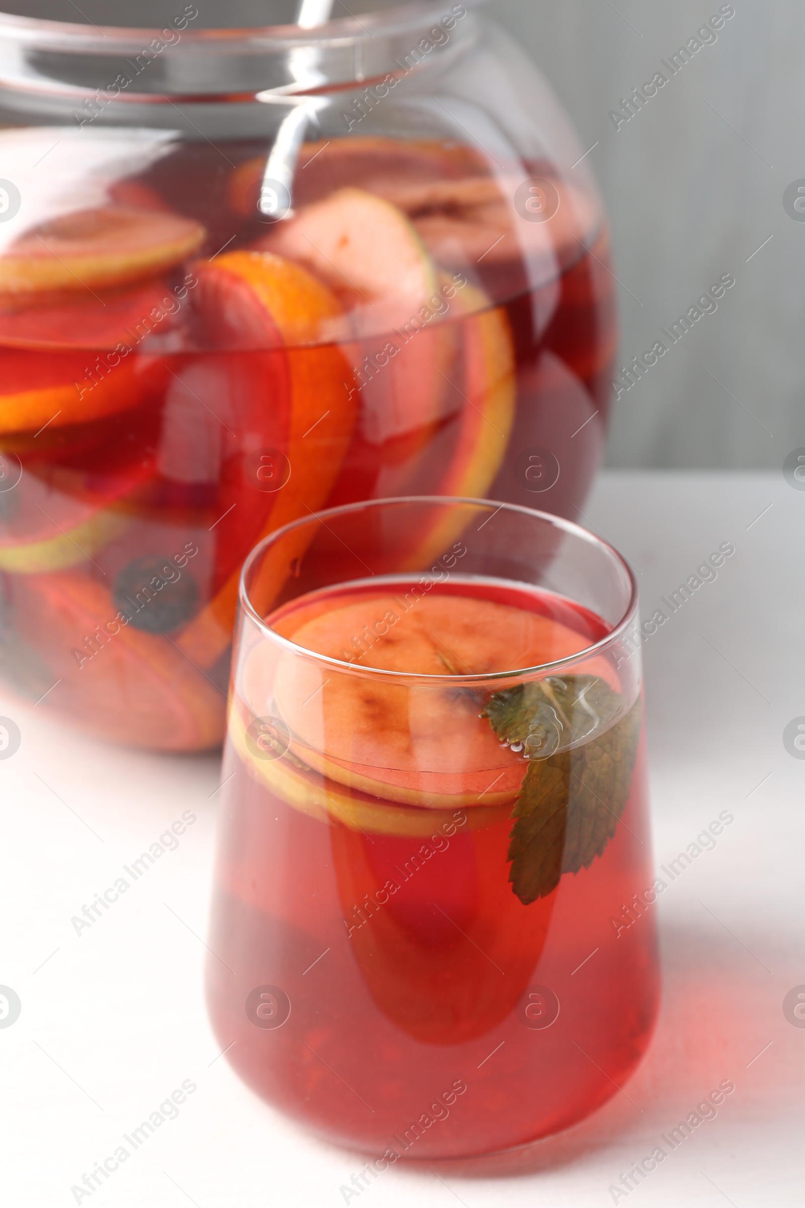 Photo of Tasty fruity punch on white table, closeup. Refreshing drink