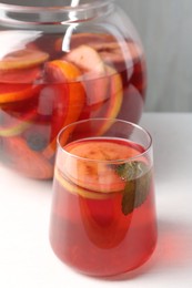 Photo of Tasty fruity punch on white table, closeup. Refreshing drink