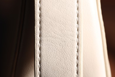 Photo of White leather bag on blurred background, closeup
