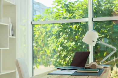 Photo of Home workplace. Laptop, headphones, coffee and stationery on wooden table, space for text