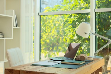 Photo of Home workplace. Laptop, headphones, coffee and stationery on wooden table, space for text