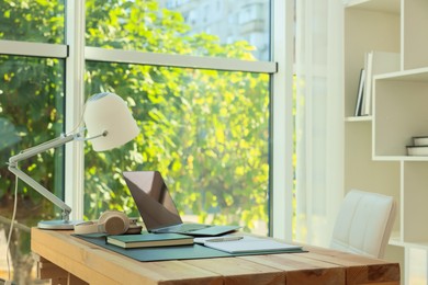 Photo of Home workplace. Laptop, headphones, coffee and stationery on wooden table, space for text