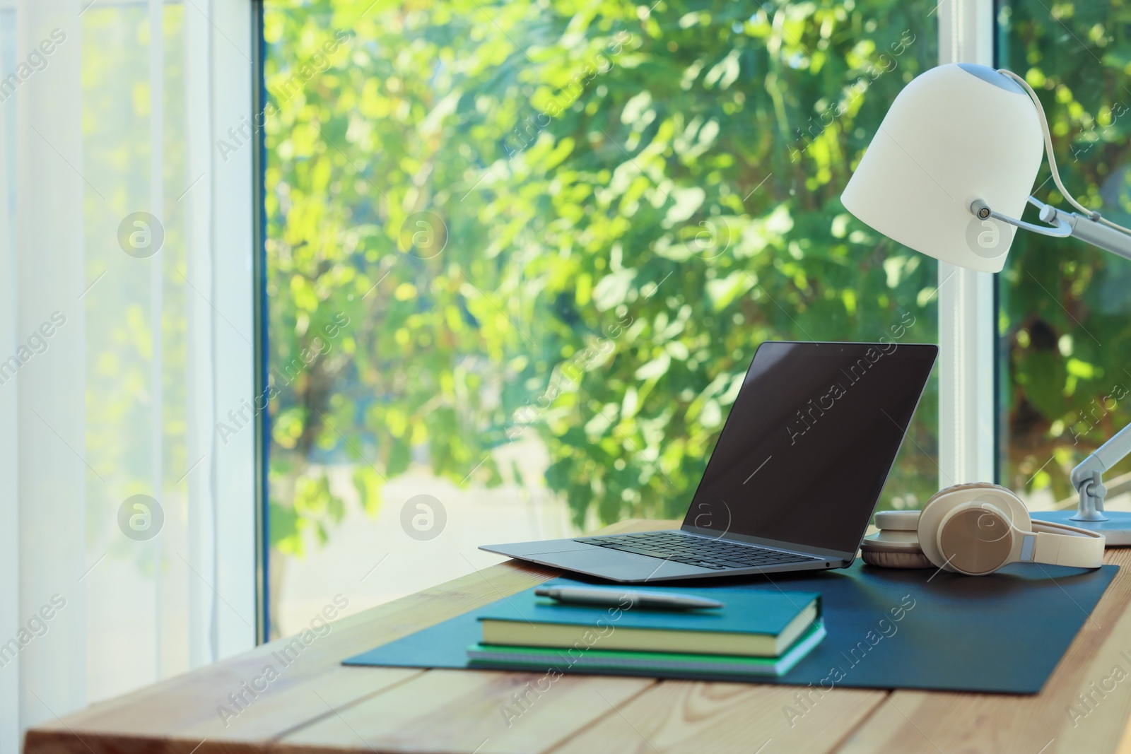 Home workplace. Laptop, headphones, coffee and stationery on wooden table, space for text Photo of Home workplace. Laptop, headphones, coffee and stationery on wooden table, space for text