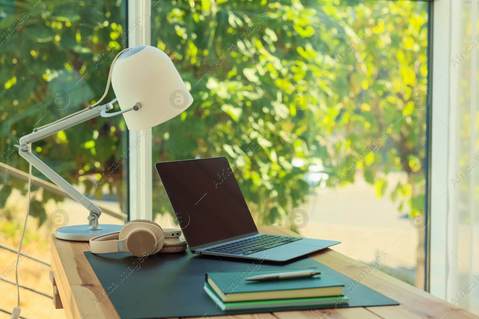Photo of Home workplace. Laptop, headphones, coffee and stationery on wooden table