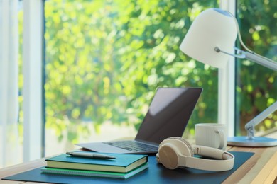 Photo of Home workplace. Laptop, headphones, coffee and stationery on wooden table