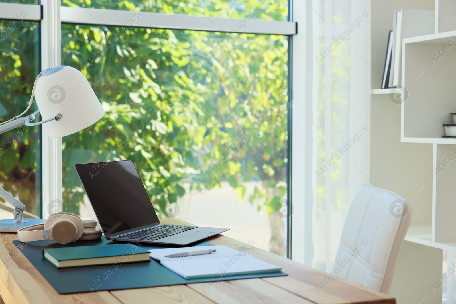 Photo of Home workplace. Laptop, headphones, coffee and stationery on wooden table, space for text