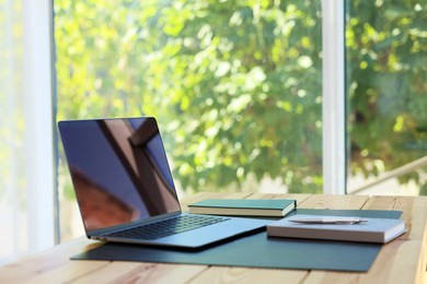 Photo of Home workplace. Laptop and stationery on wooden table