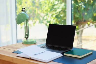 Photo of Home workplace. Laptop and stationery on wooden table