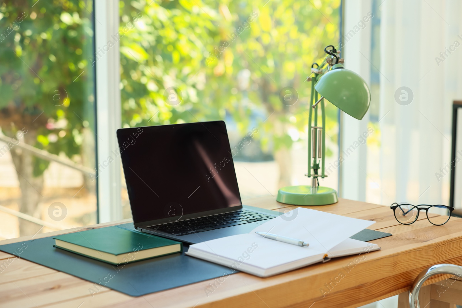 Photo of Home workplace. Laptop and stationery on wooden table