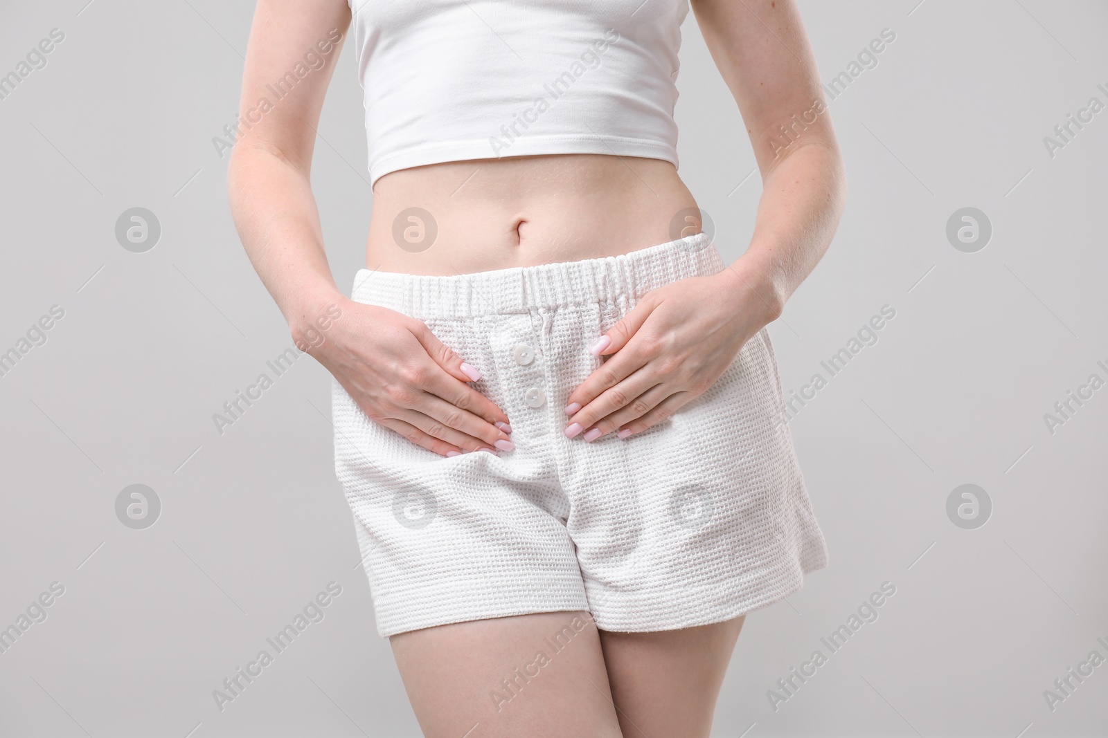 Photo of Woman suffering from cystitis symptoms on light grey background, closeup