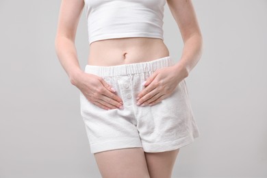 Photo of Woman suffering from cystitis symptoms on light grey background, closeup