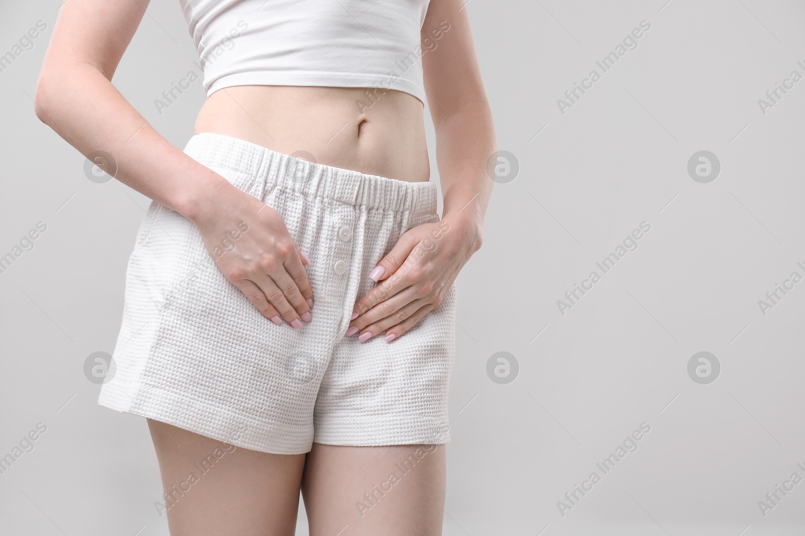 Photo of Woman suffering from cystitis symptoms on light grey background, closeup. Space for text