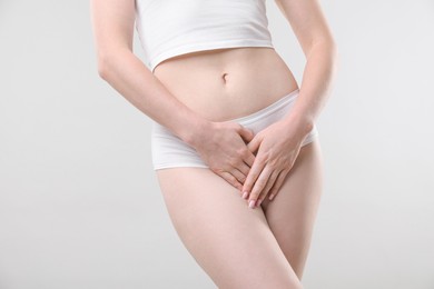 Photo of Woman suffering from cystitis symptoms on light grey background, closeup