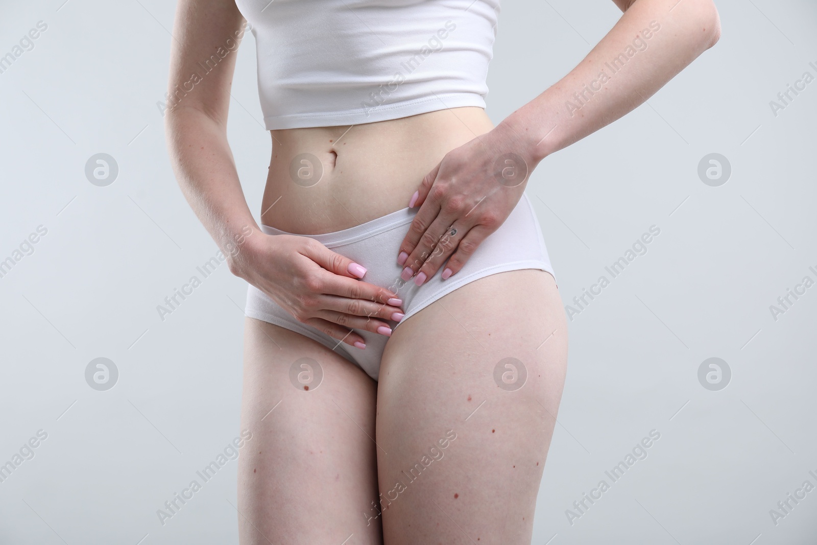Photo of Woman suffering from cystitis symptoms on light grey background, closeup