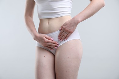 Photo of Woman suffering from cystitis symptoms on light grey background, closeup