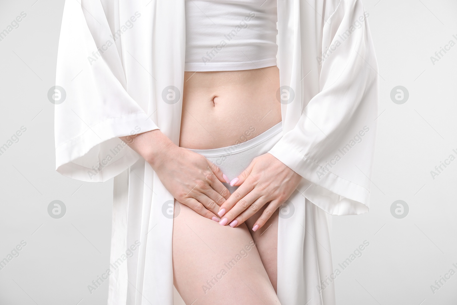 Photo of Woman suffering from cystitis symptoms on light grey background, closeup