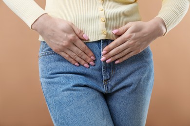 Photo of Woman suffering from cystitis symptoms on dark beige background, closeup