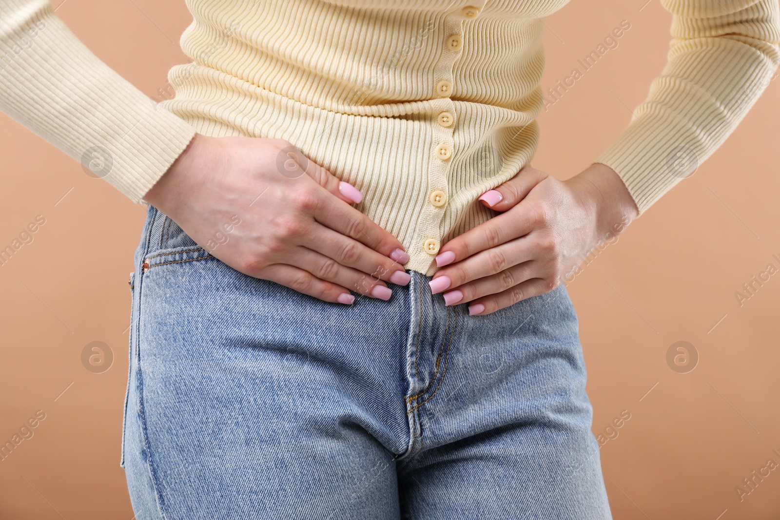 Photo of Woman suffering from cystitis symptoms on dark beige background, closeup