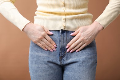 Photo of Woman suffering from cystitis symptoms on dark beige background, closeup