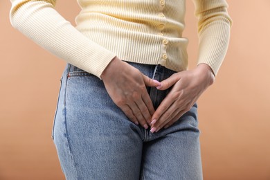 Photo of Woman suffering from cystitis symptoms on dark beige background, closeup