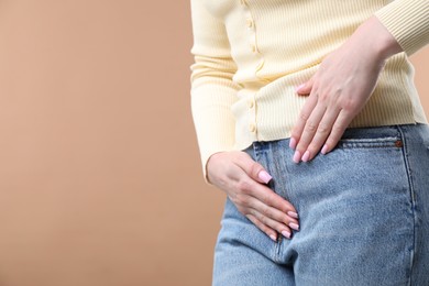 Photo of Woman suffering from cystitis symptoms on dark beige background, closeup. Space for text