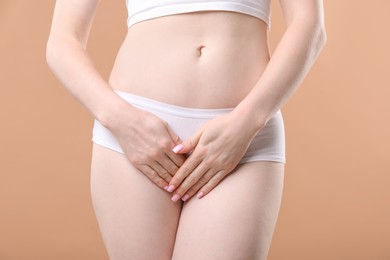 Photo of Woman suffering from cystitis symptoms on dark beige background, closeup