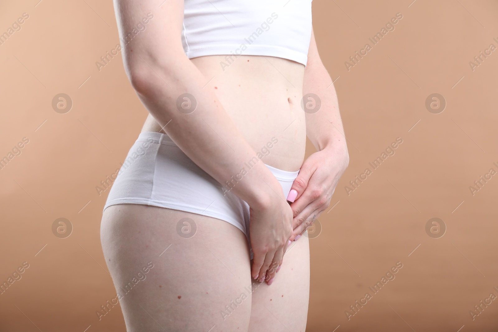 Photo of Woman suffering from cystitis symptoms on dark beige background, closeup