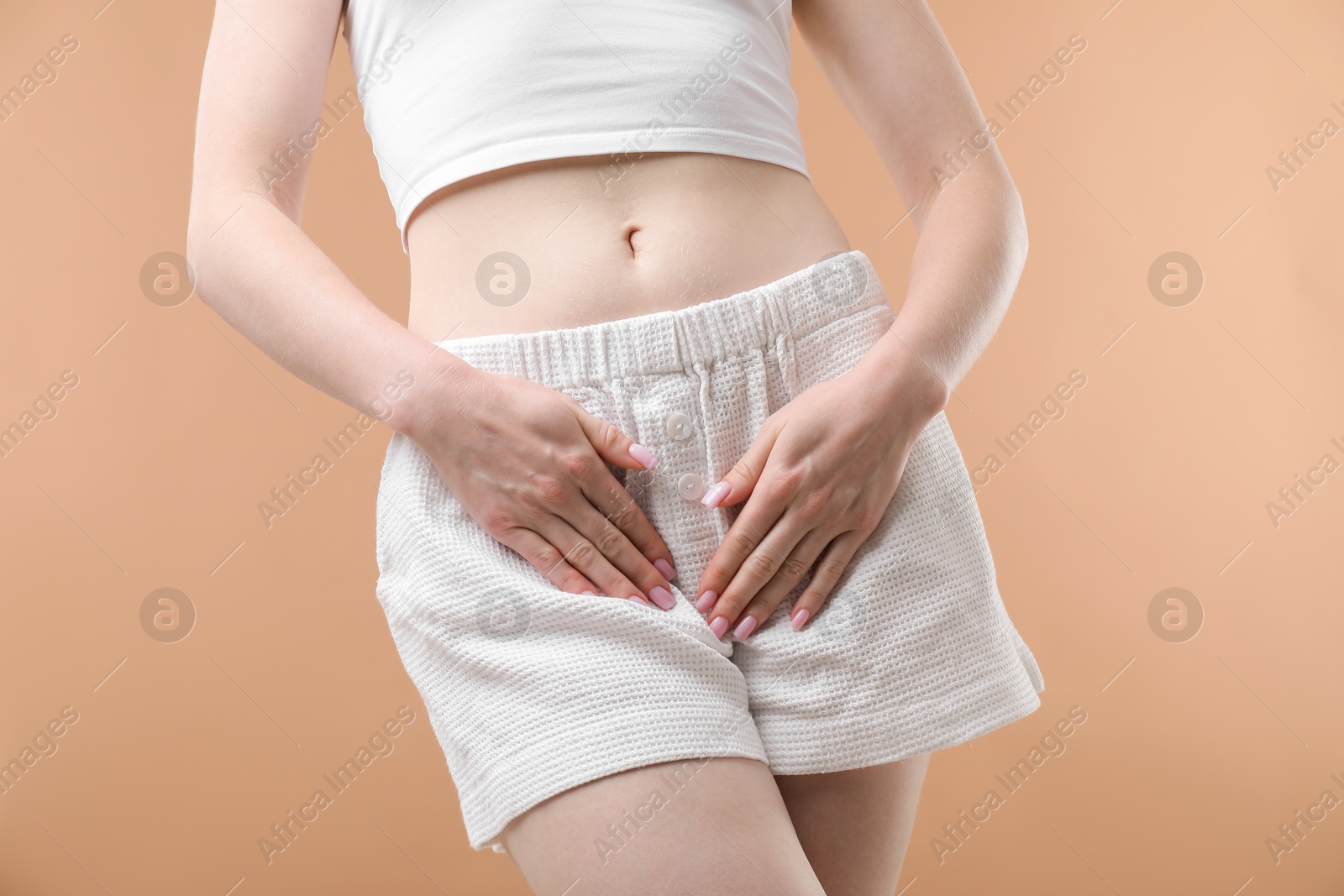 Photo of Woman suffering from cystitis symptoms on dark beige background, closeup