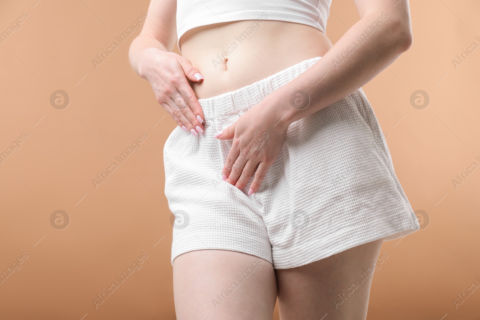 Photo of Woman suffering from cystitis symptoms on dark beige background, closeup