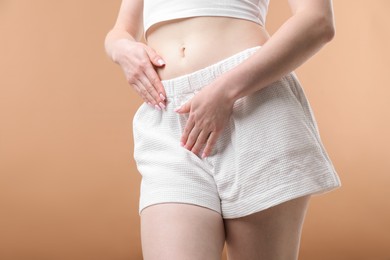 Photo of Woman suffering from cystitis symptoms on dark beige background, closeup