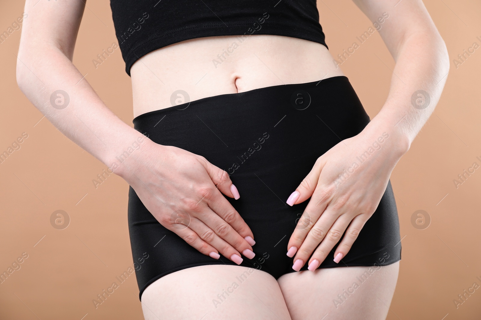 Photo of Woman suffering from cystitis symptoms on dark beige background, closeup