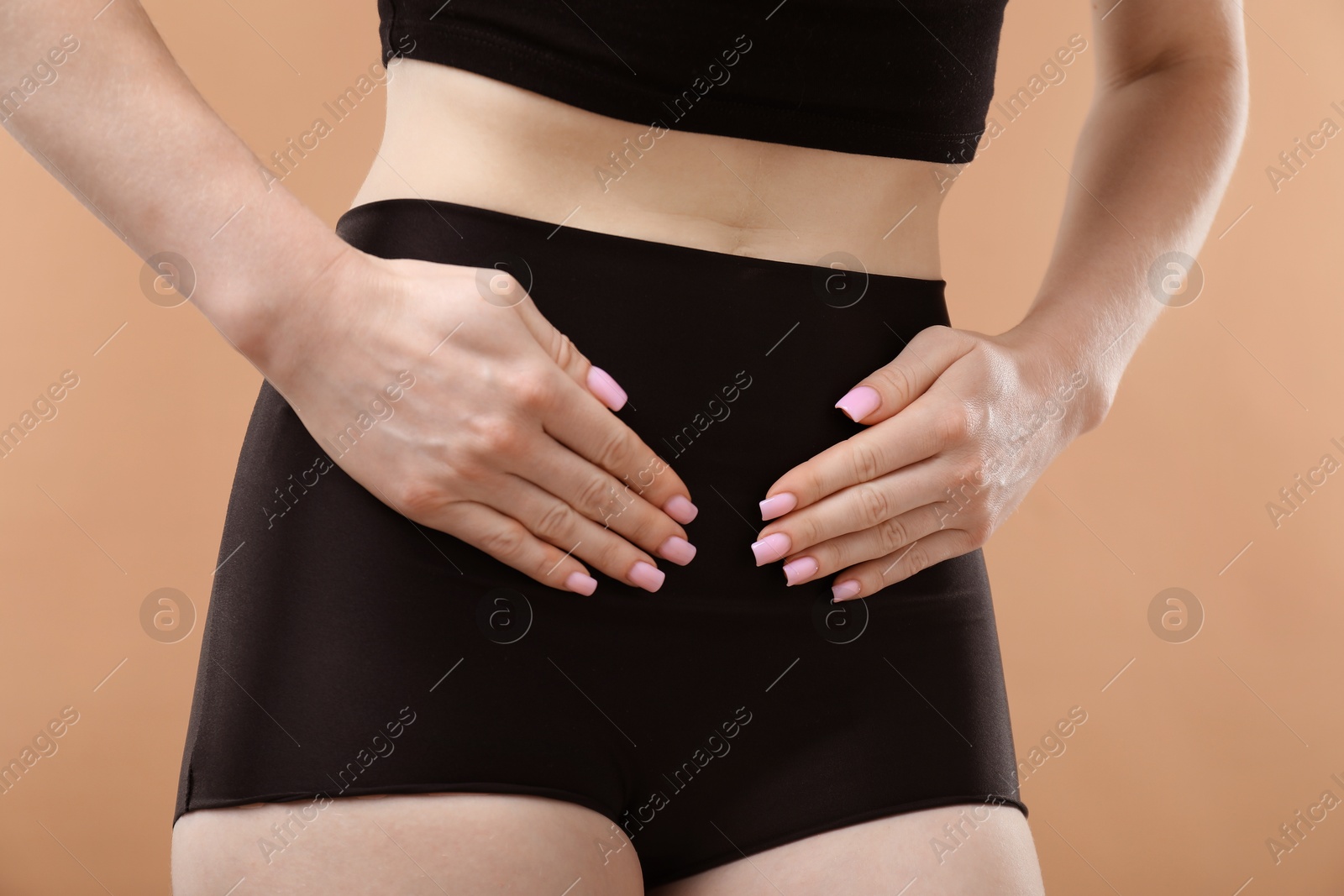 Photo of Woman suffering from cystitis symptoms on dark beige background, closeup