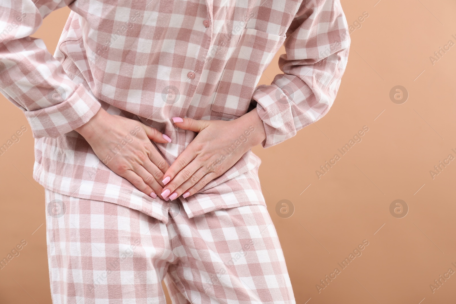 Photo of Woman suffering from cystitis symptoms on dark beige background, closeup. Space for text