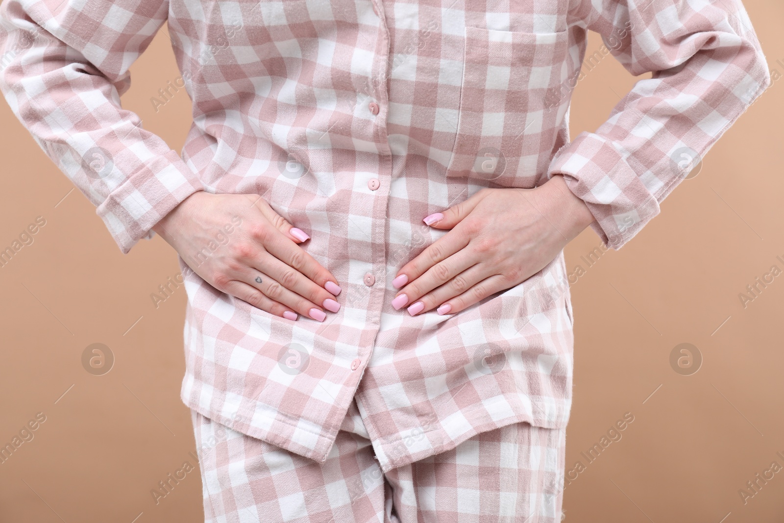 Photo of Woman suffering from cystitis symptoms on dark beige background, closeup