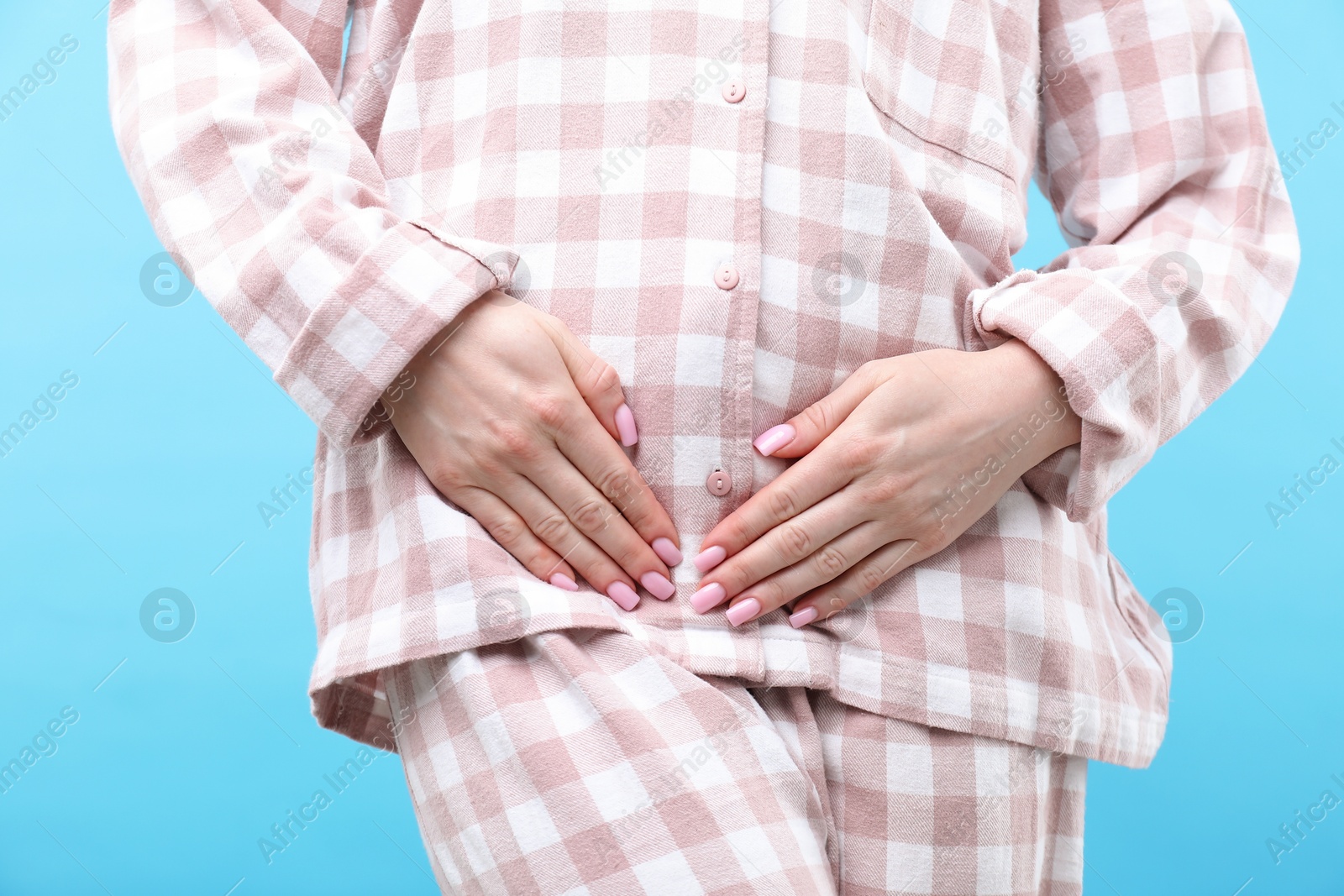 Photo of Woman suffering from cystitis symptoms on light blue background, closeup