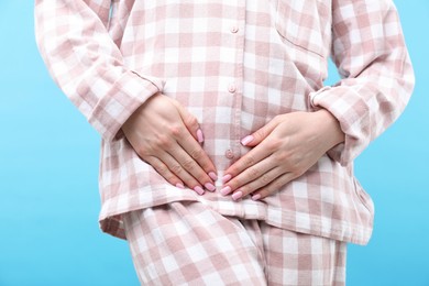 Photo of Woman suffering from cystitis symptoms on light blue background, closeup